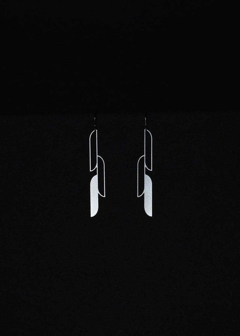A close up of a woman wearing silver earrings on a black background