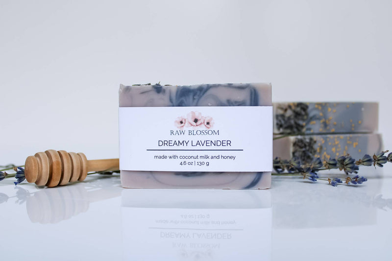 Two soap bars with a blue design on a white background with lavender flowers and a honey dipper.