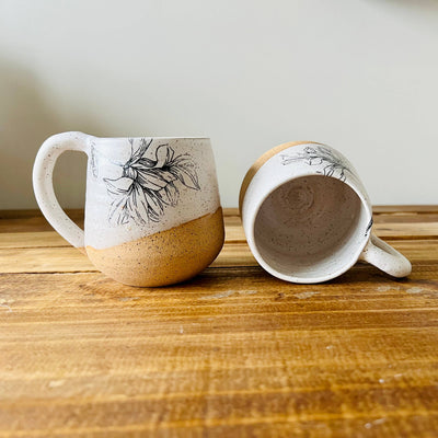 Two ceramic mugs with floral designs on a wooden surface