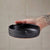 Person holding a black ceramic dish against a tiled wall background