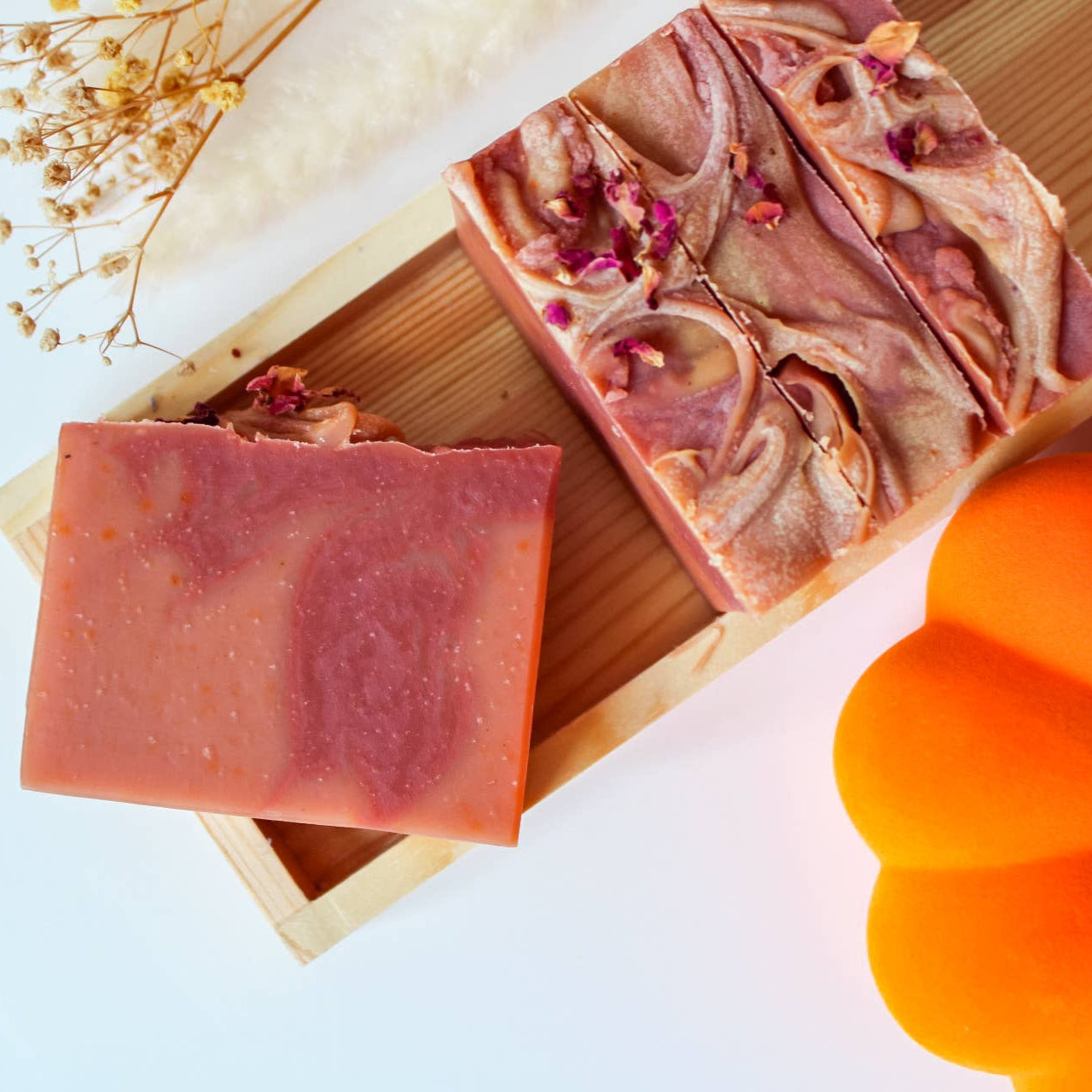 Soap bars with a pumpkin and dried flowers on a light background
