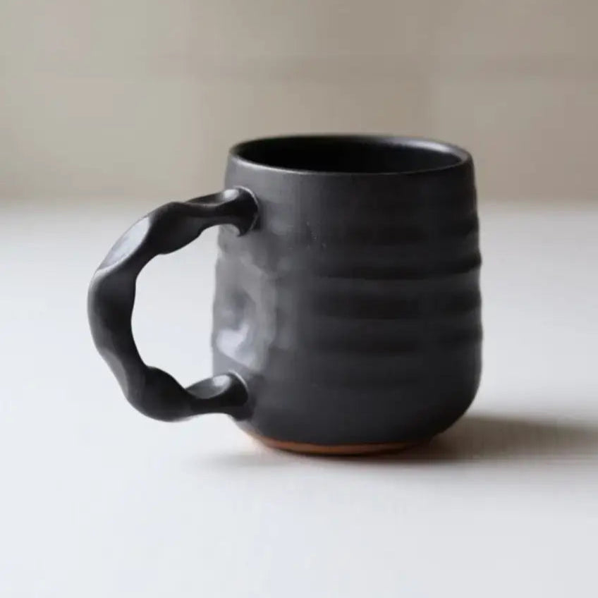 Black ceramic mug on a light surface with a neutral background