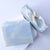 Two bars of soap with a gold leaf design on a light purple background