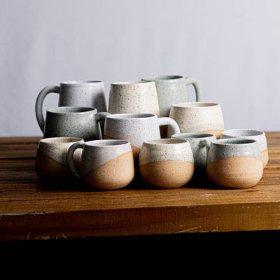 Set of ceramic mugs on a wooden surface with a plain background