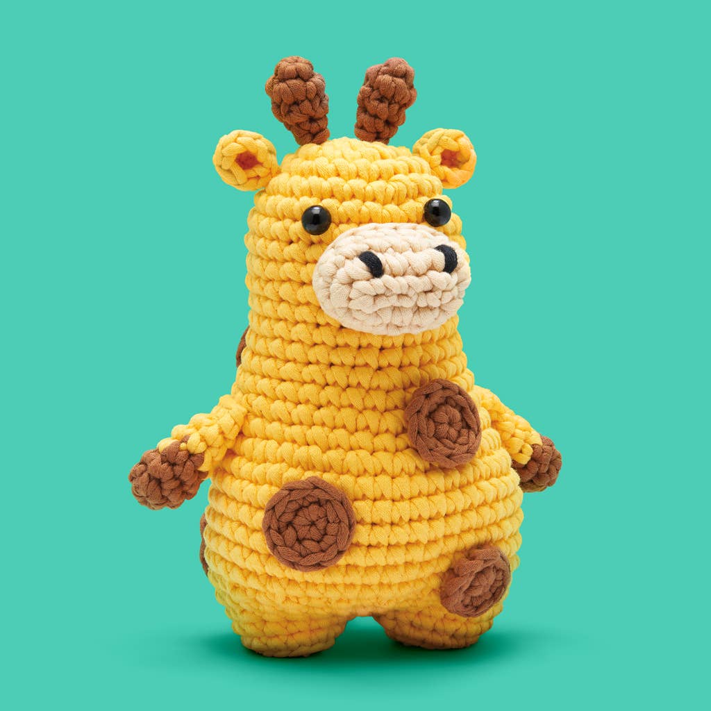 Crocheted giraffe toy on a teal background