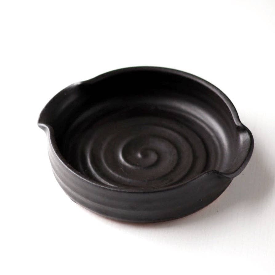 Black ceramic bowl with spiral design on a white background