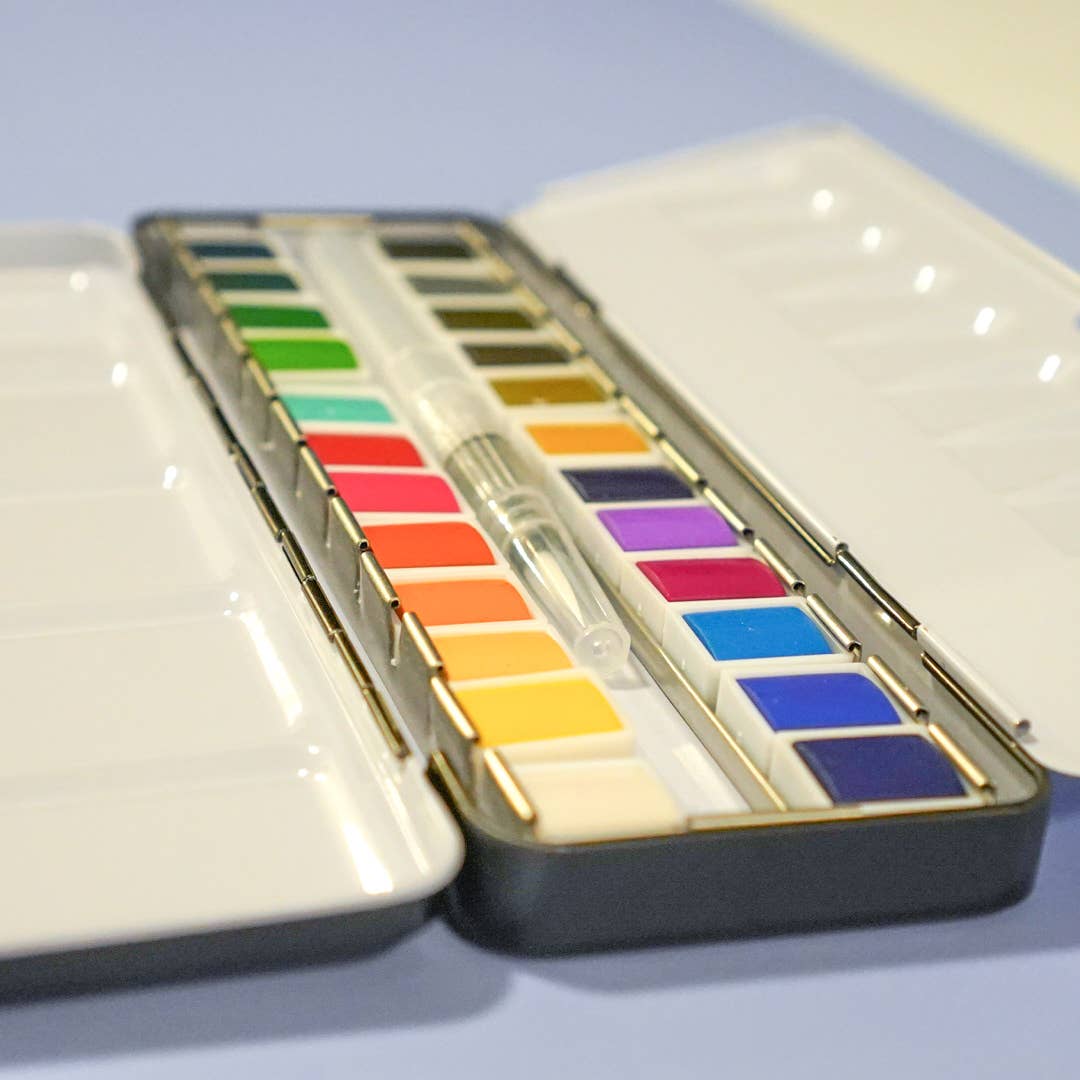 Set of watercolor paints in a case on a light blue background