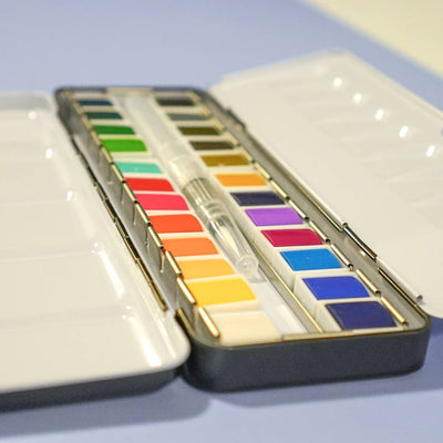 Set of watercolor paints in a case on a light blue background