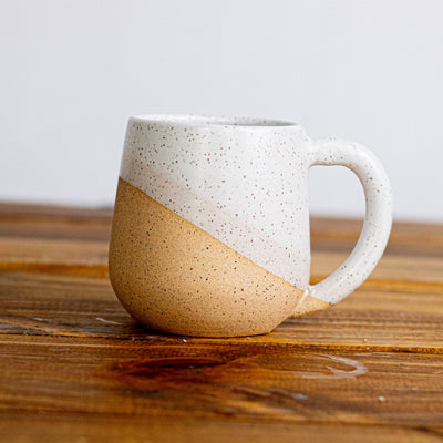 Two-toned ceramic mug on a wooden surface with a white background