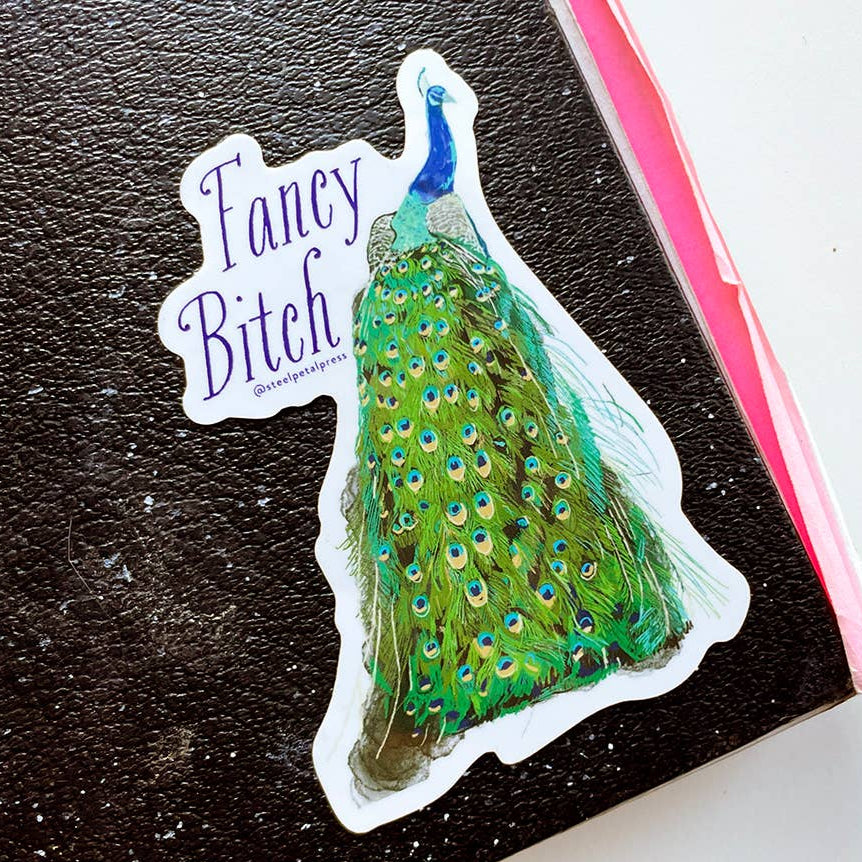 Peacock sticker with 'Fancy Bitch' text on a black surface
