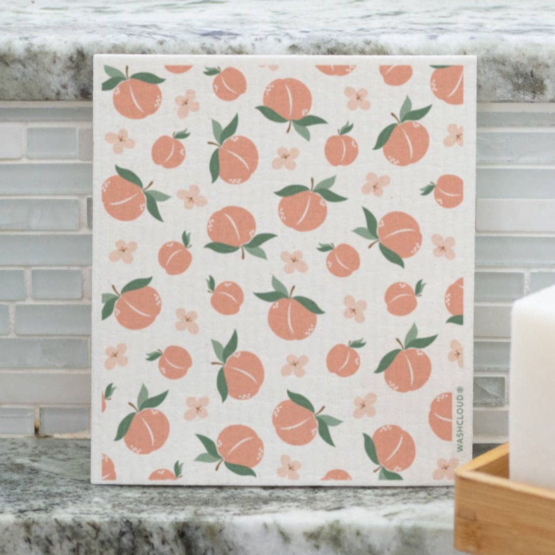 Patterned towel with peaches on a kitchen counter next to a sink