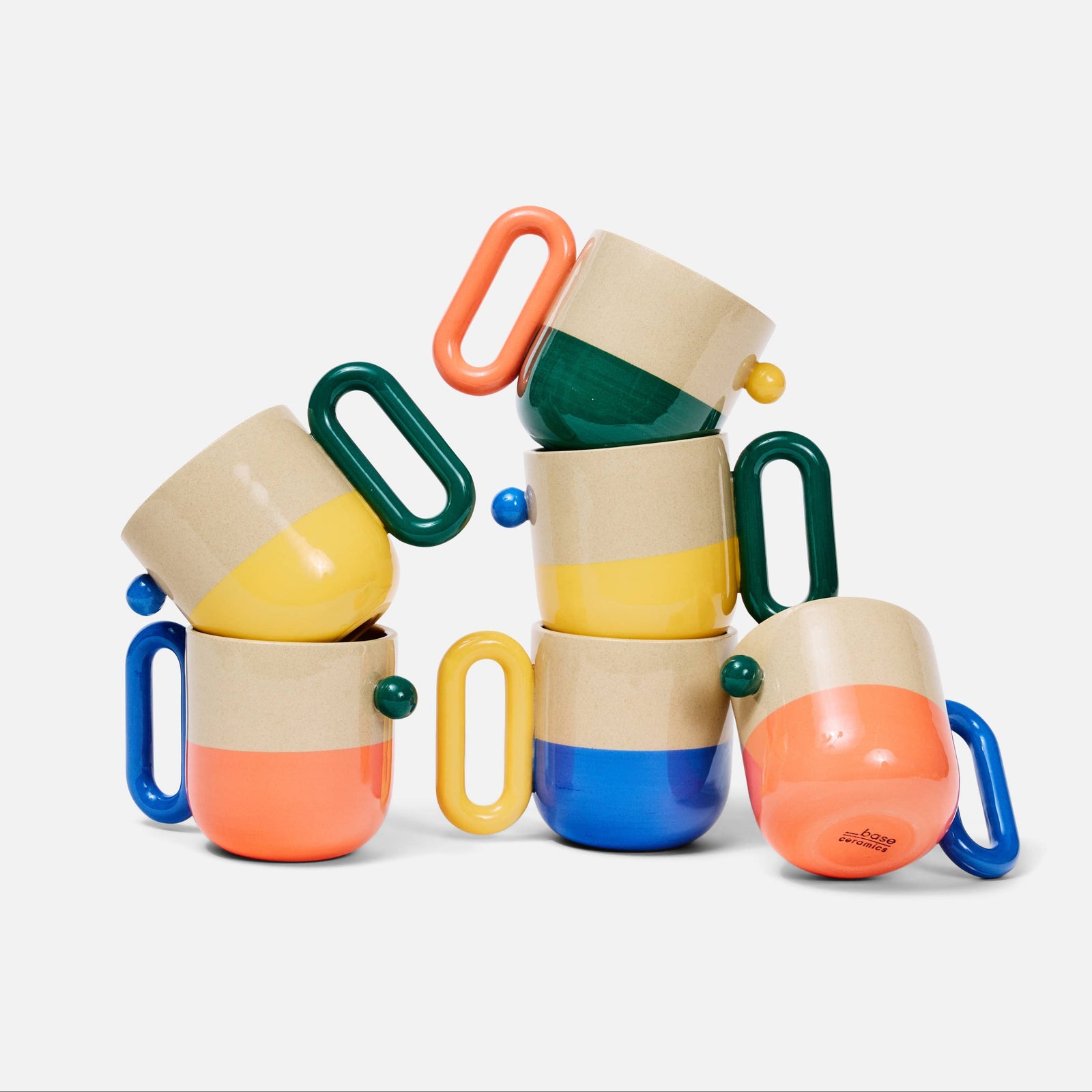 A set of colorful mugs with handles, stacked in a playful pile on a white background.