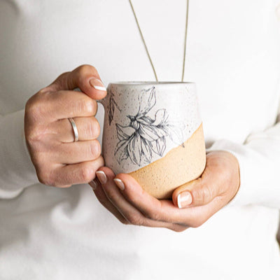 Person holding a ceramic mug with a white background