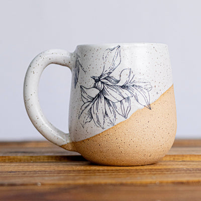 Two-tone ceramic mug with floral design on a wooden surface