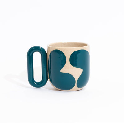 A ceramic mug with a bold abstract design, featuring a dark teal handle and body with a cream-colored organic pattern, set against a plain white background.