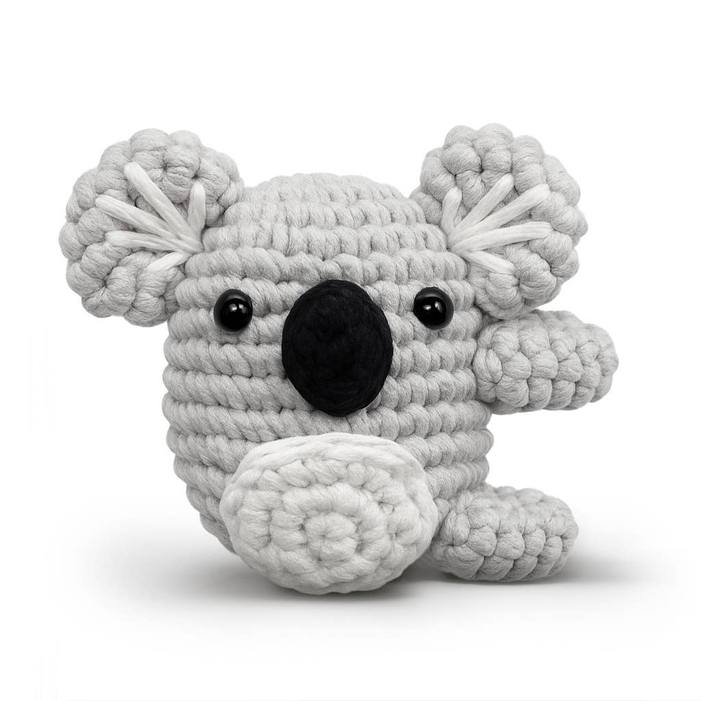 A crocheted koala plush toy in light gray and white yarn with a black nose and black bead eyes, photographed on a clean white background.