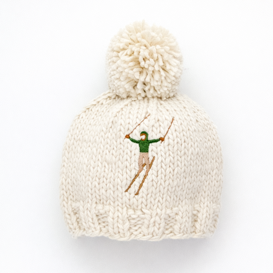 Knitted beanie with pom-pom and embroidered design on a white background