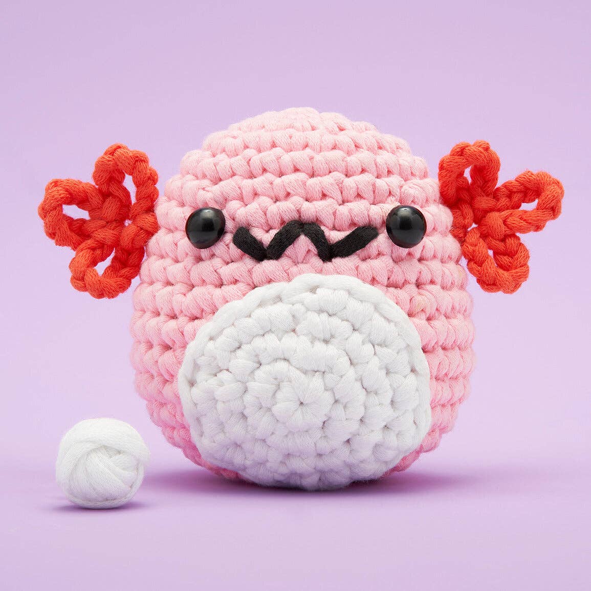 Crocheted pink Axolotl toy on a purple background