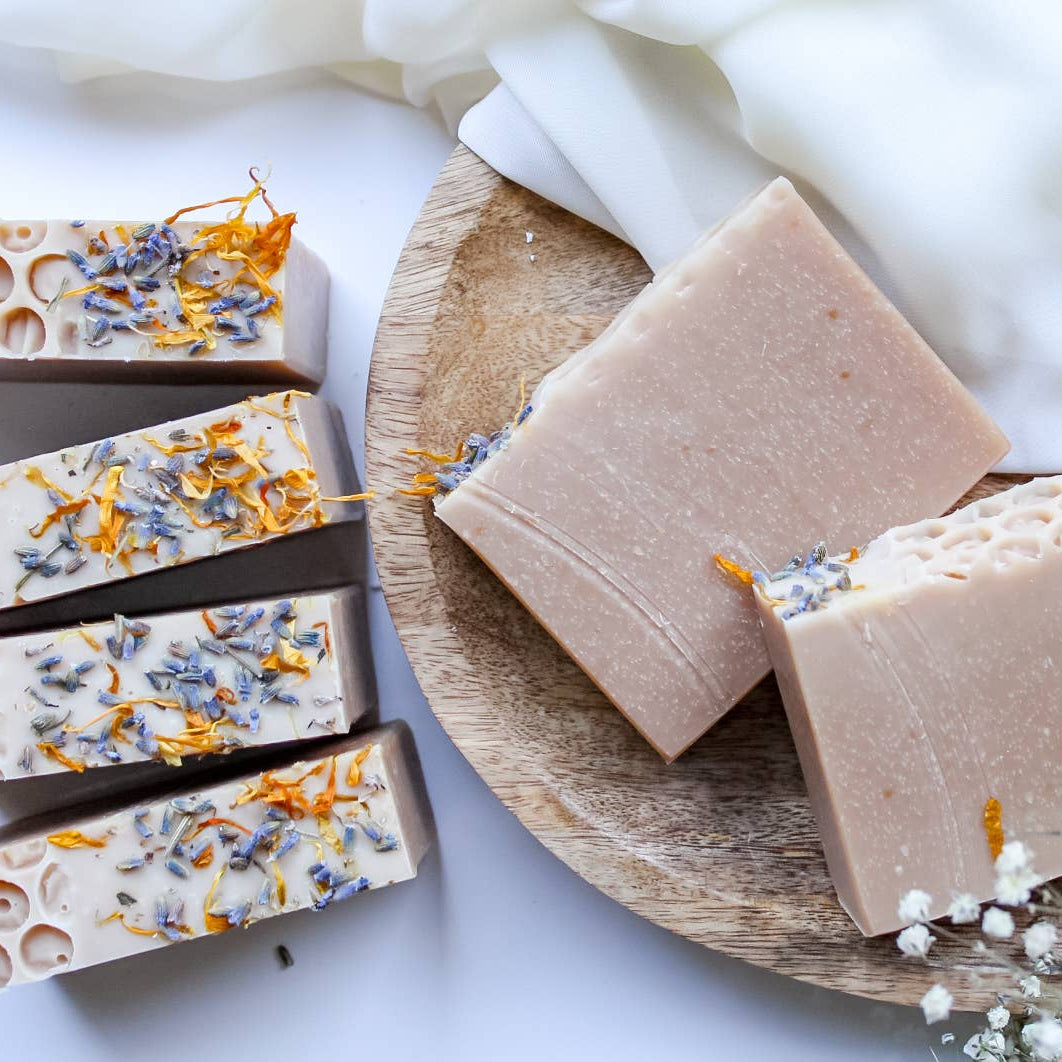 Handmade soap bars with natural designs on a wooden plate and white background