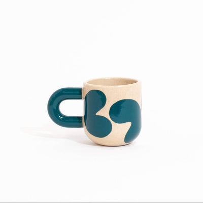 cream mug with a decorative teal blobs on a white background