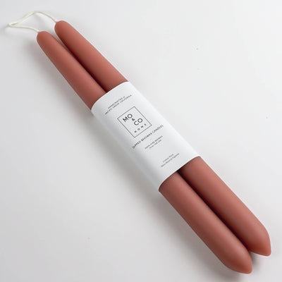 Two terracotta candles wrapped in a white label on a white background