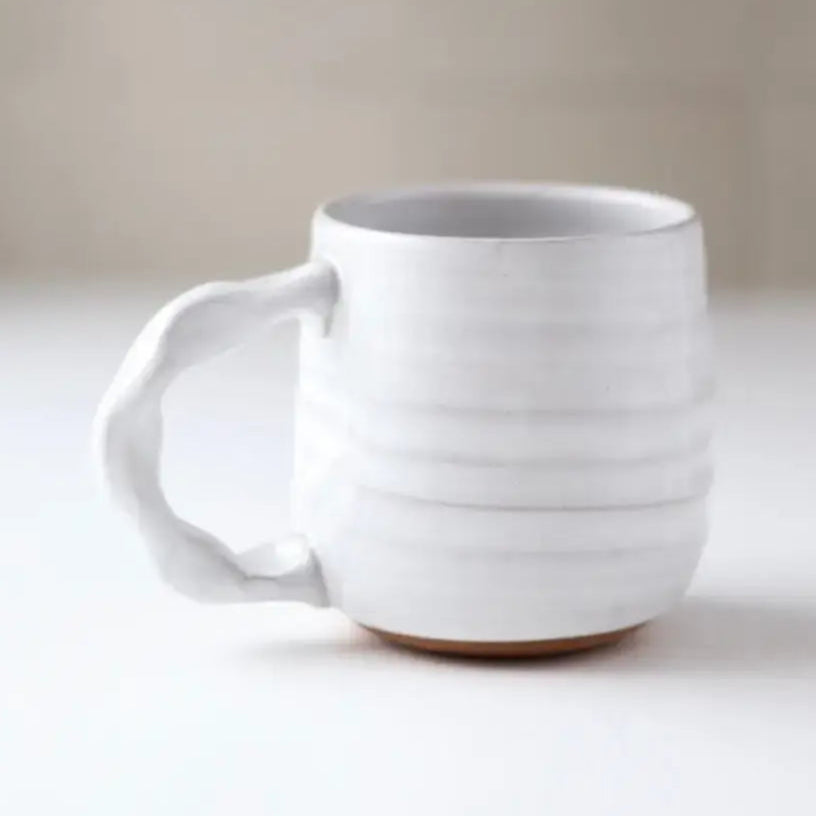 White ceramic mug on a light surface with a neutral background