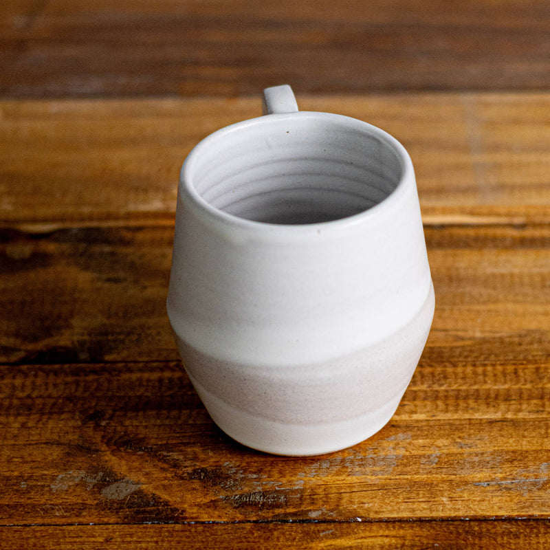 White ceramic mug on a wooden surface with a plain background