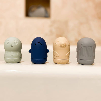 Four colorful bath toys on a white surface with a neutral background