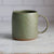 Green ceramic mug on a marble surface with a tiled wall background