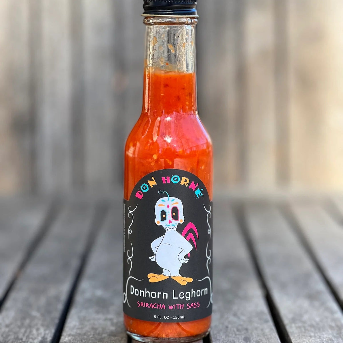 Hot sauce bottle with a cartoon character label on a wooden surface