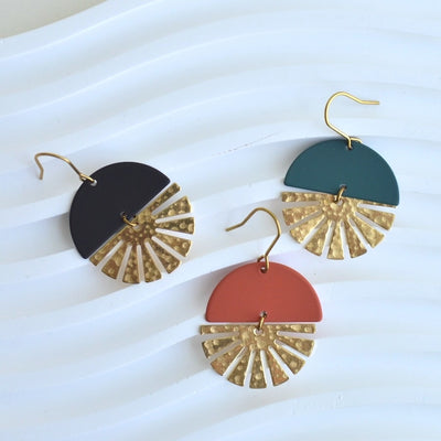 Three round earrings in different colors on a white background.