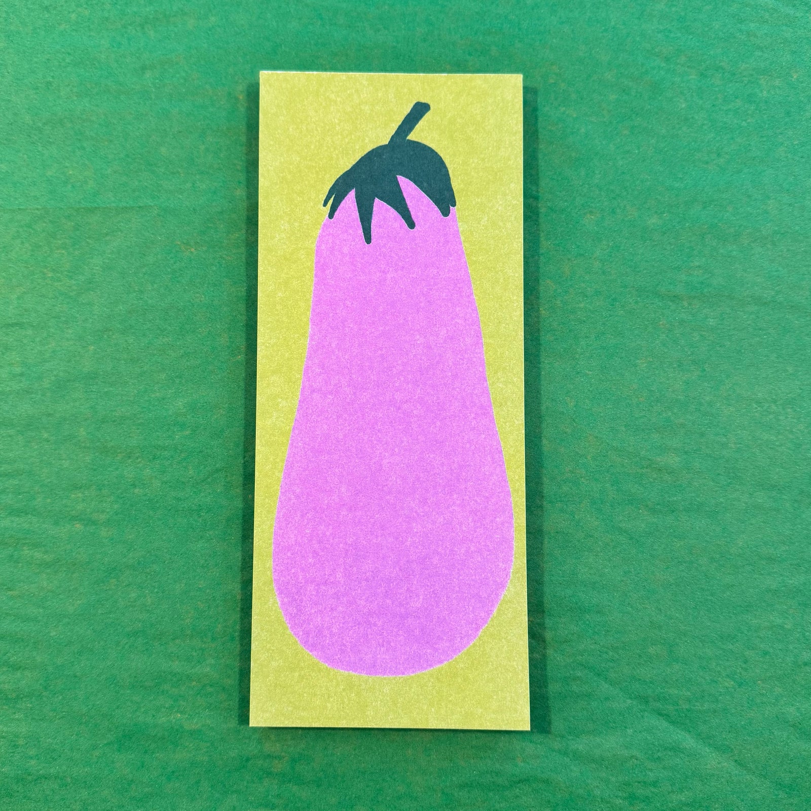 A green notepad with an illustration of an eggplant on a green background. 