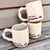 Two ceramic mugs with 'We love Occoquan, VA!' text on a wooden surface.