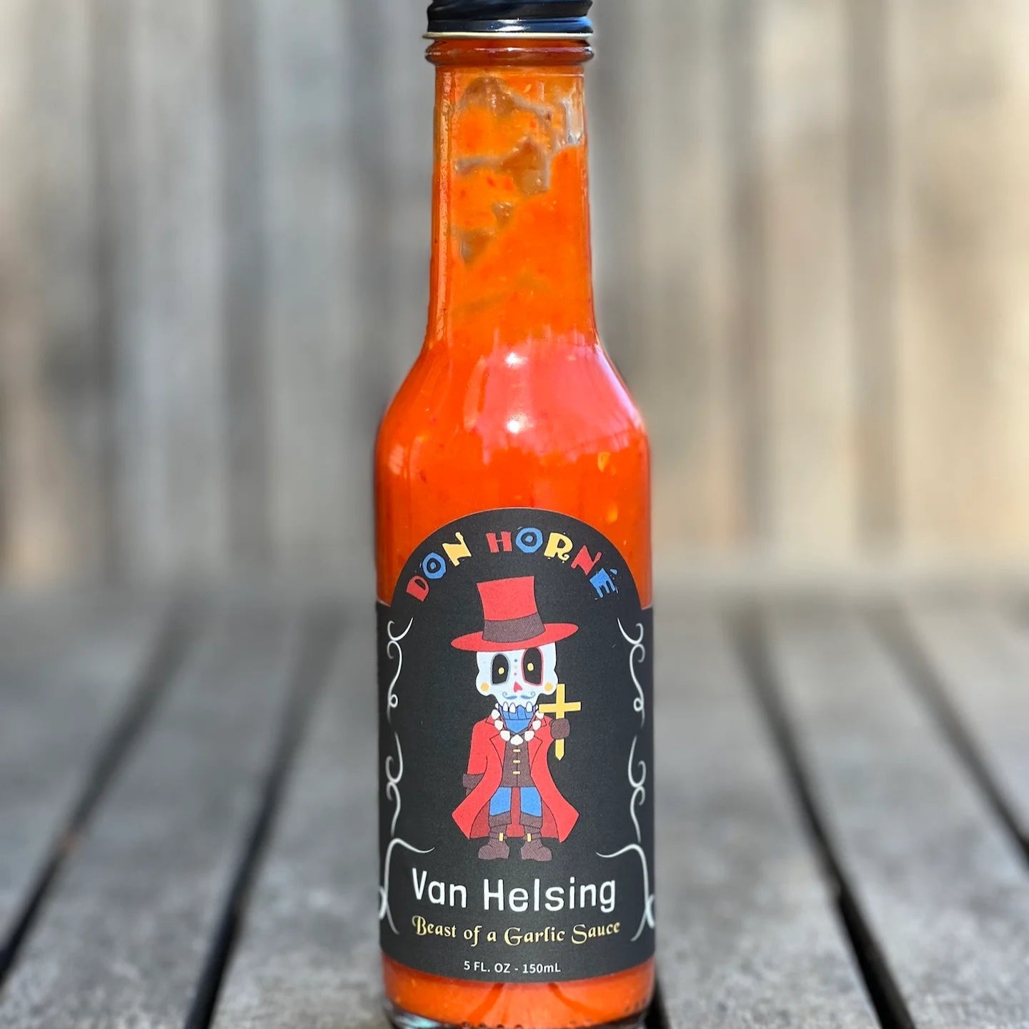 Hot sauce bottle with a label featuring a character on a wooden surface
