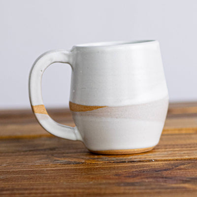 White ceramic mug on a wooden surface with a plain background