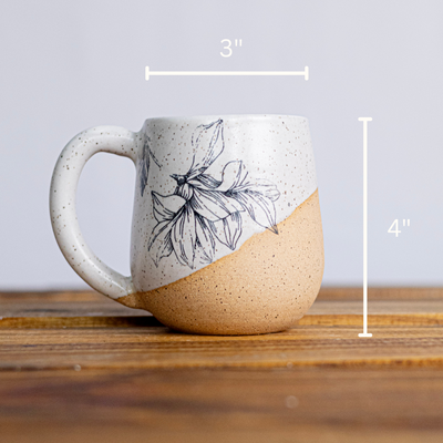 Ceramic mug with floral design on a wooden surface, with measurements indicated.