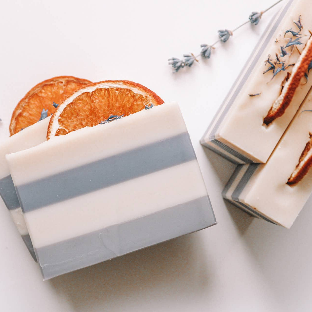 Bar of soap with gray stripes and dried orange slices on a white background