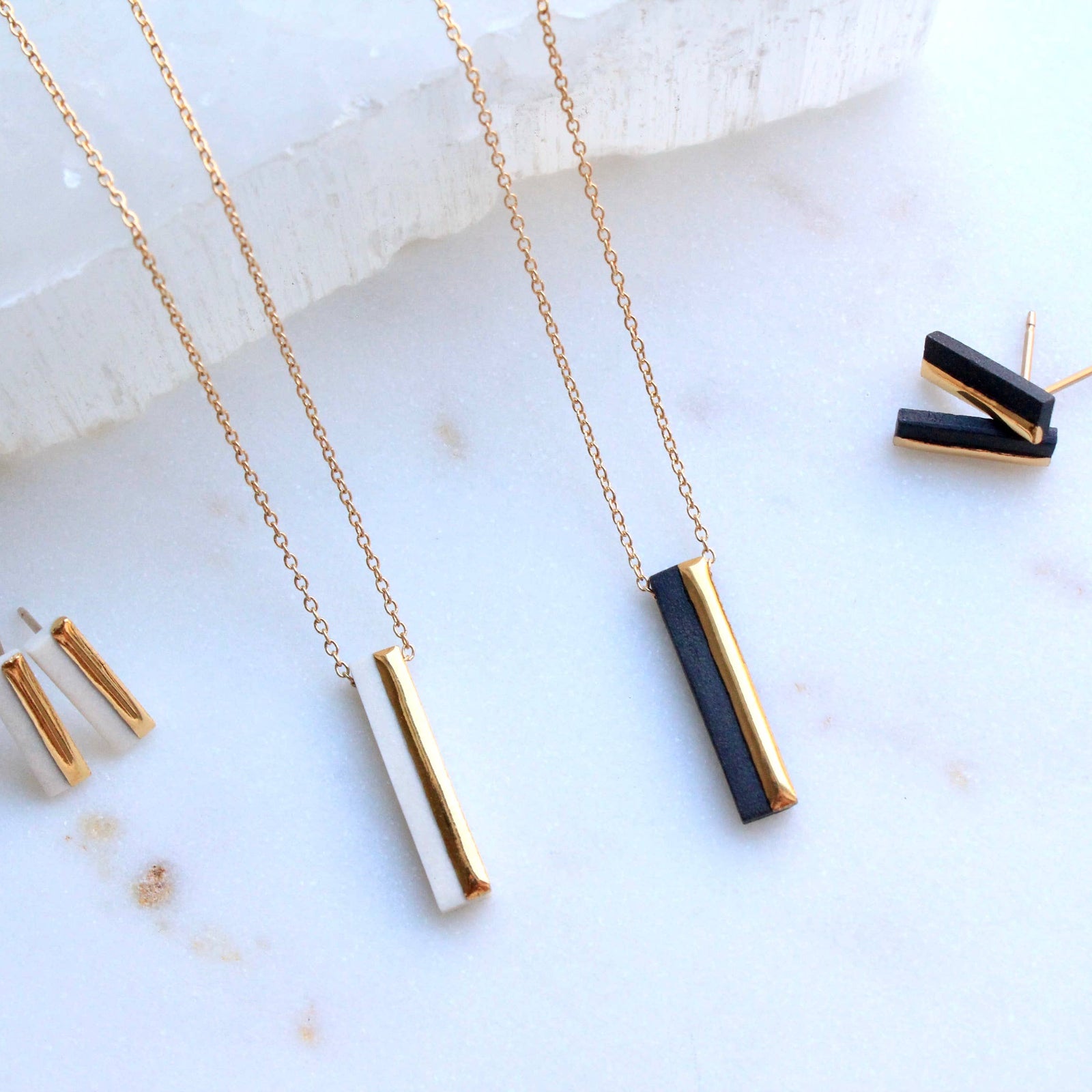 Gold and black necklaces on a marble surface