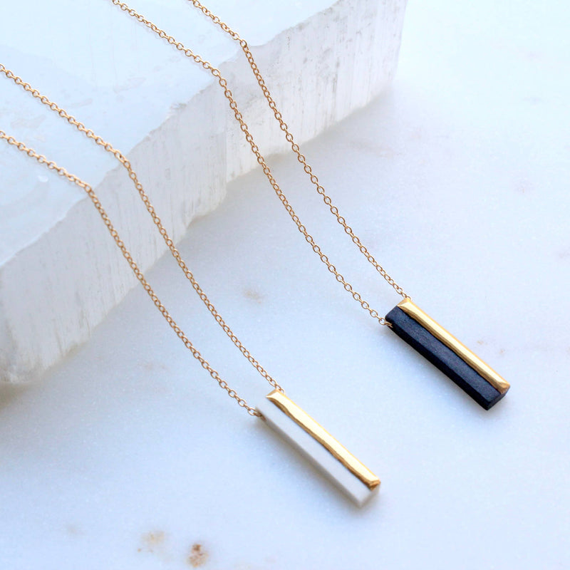 Gold and black necklaces on a marble surface