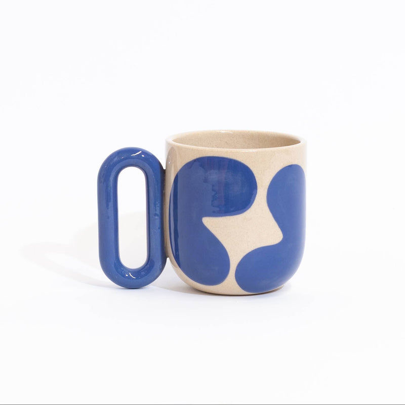 Three ceramic mugs with bold abstract color-blocked patterns in blue, orange, and teal on a cream base, arranged on a clean white background.