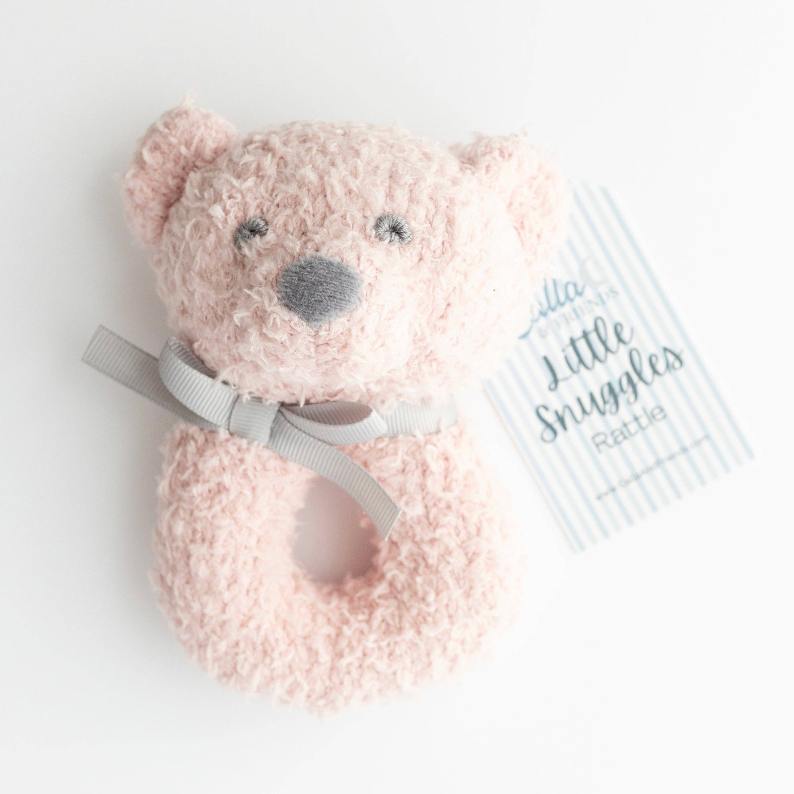 Pink teddy bear rattle with a gray bow on a white background
