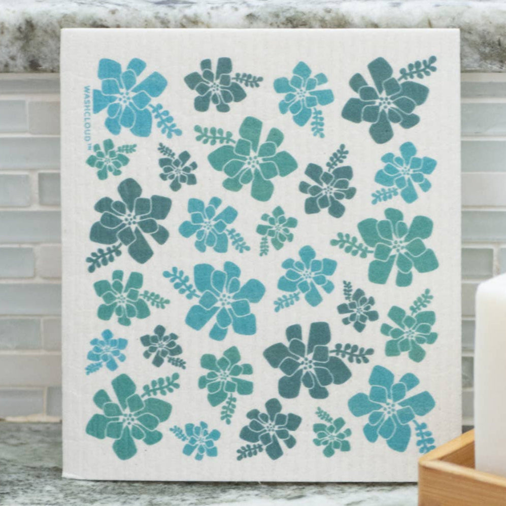 Floral-patterned dishcloth on a kitchen counter with soap and soap dish.