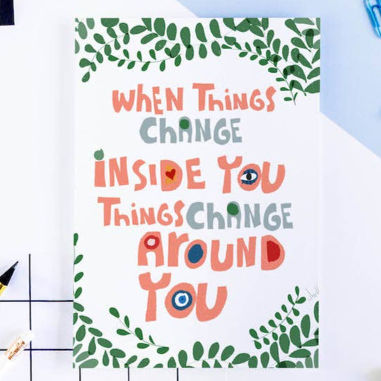 Motivational card with text 'When things change inside you, things change around you' on a desk with office supplies.