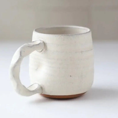 White ceramic mug on a light surface with a neutral background