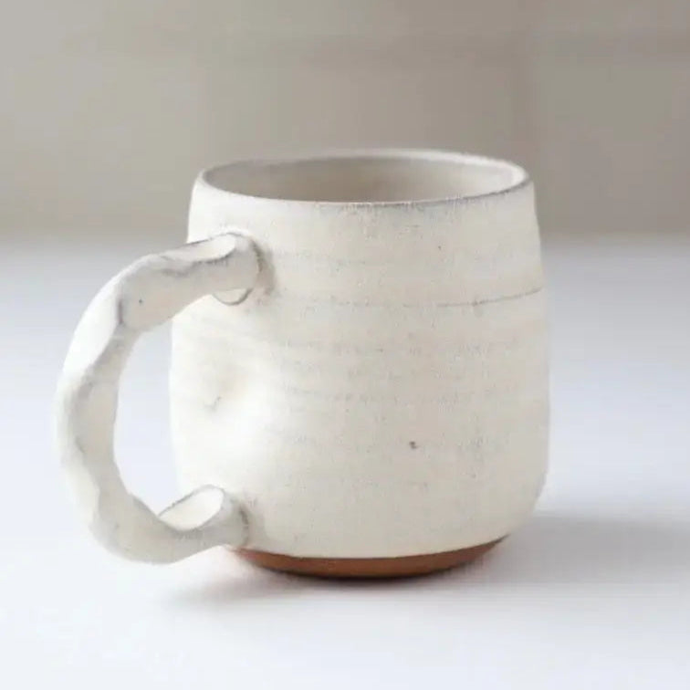 Black ceramic mug on a light surface with a neutral background