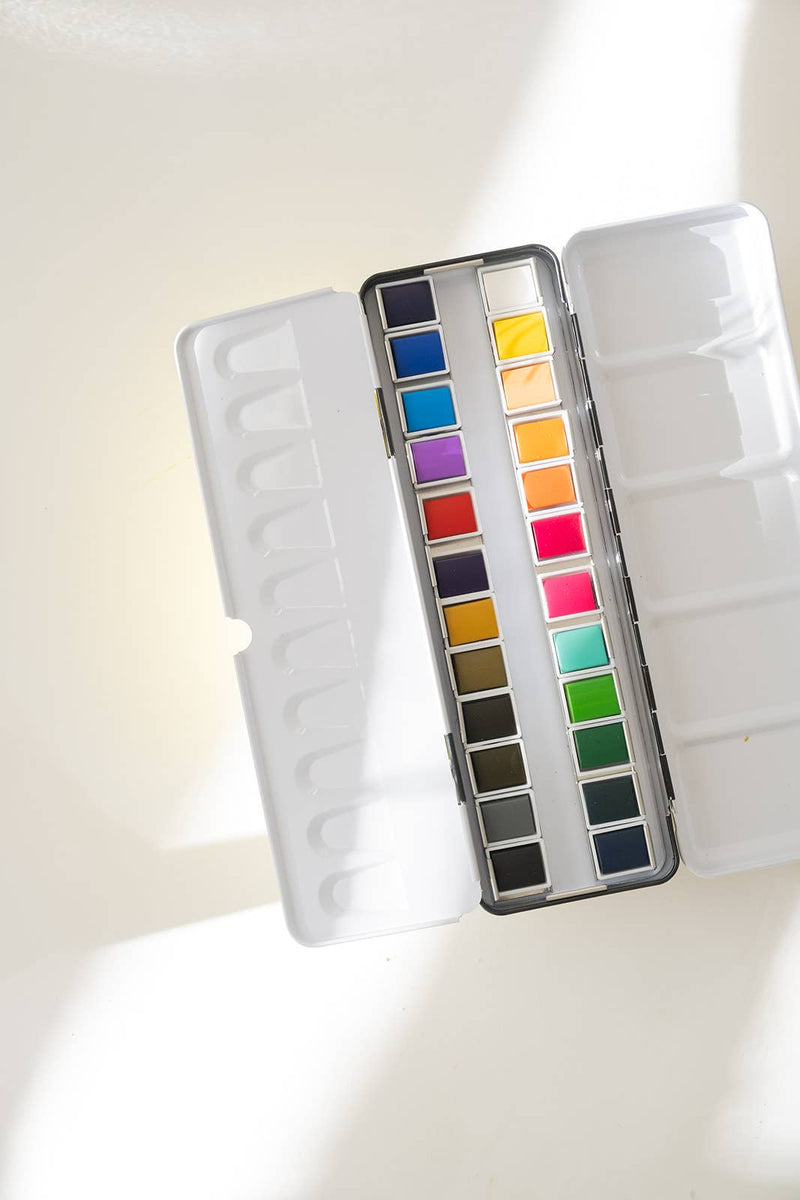 Set of watercolor paints in a case on a light blue background