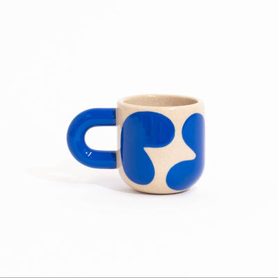 A small ceramic coffee mug with a bold blue and beige abstract pattern, photographed on a seamless white background.