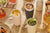 Table with various drinks in colorful tumblers and snacks on a wooden surface