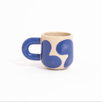 A small ceramic mug with a bold purple abstract pattern on a beige base, set against a solid white background.